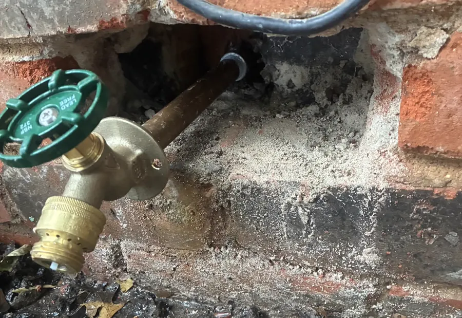 A new outdoor spigot set into a brick wall