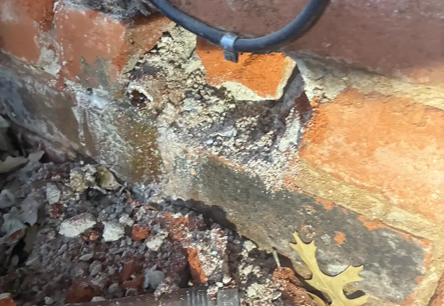 A broken water pipe exposed inside a brick wall